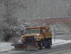 Orange truck plowing snow on street
