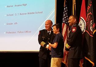 Aryana High receives graduation certificate from Police Chief Scott Booth, left, and Deputy Police C