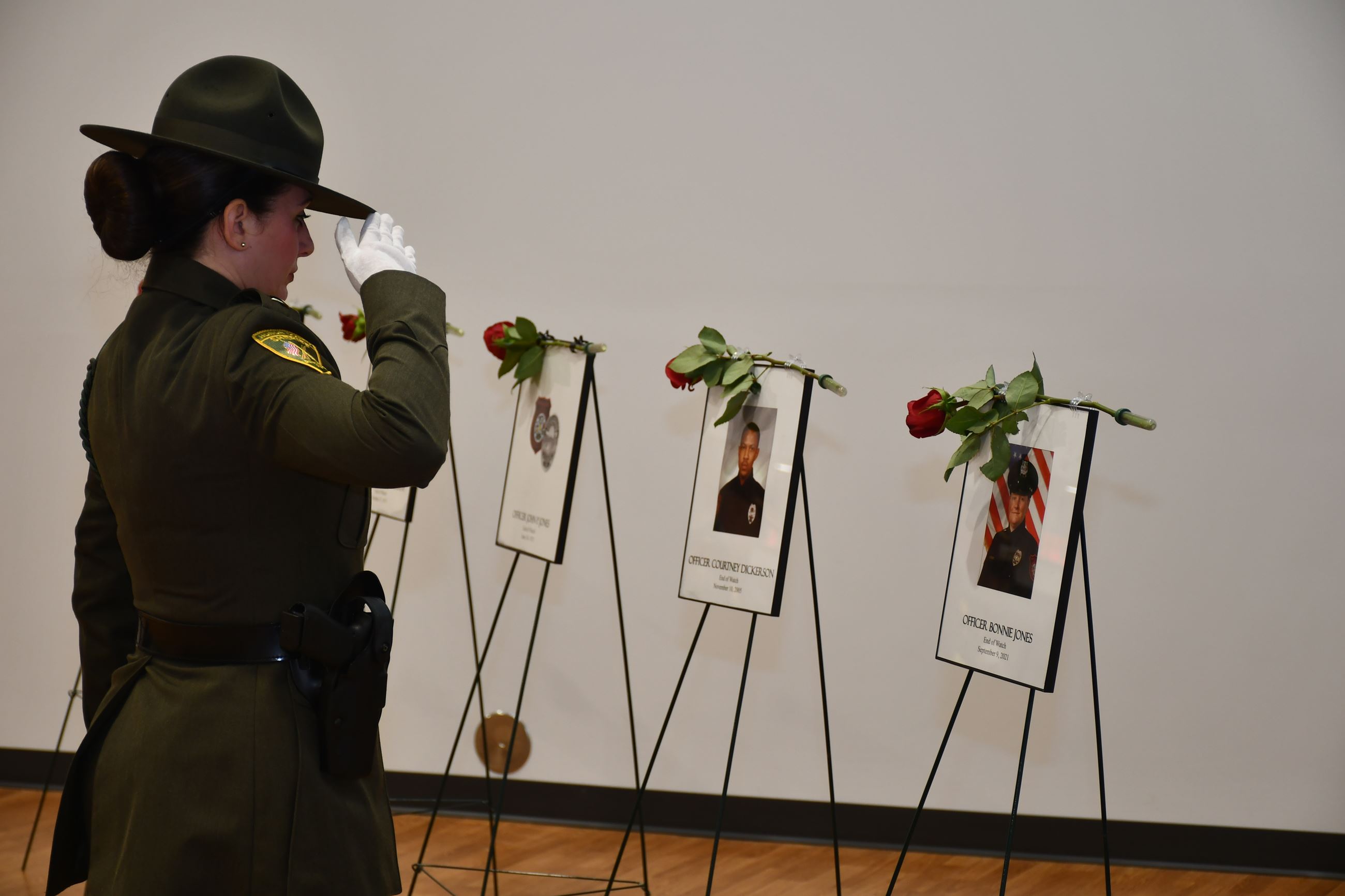 Officer saluting a fallen officer after placing a rose.