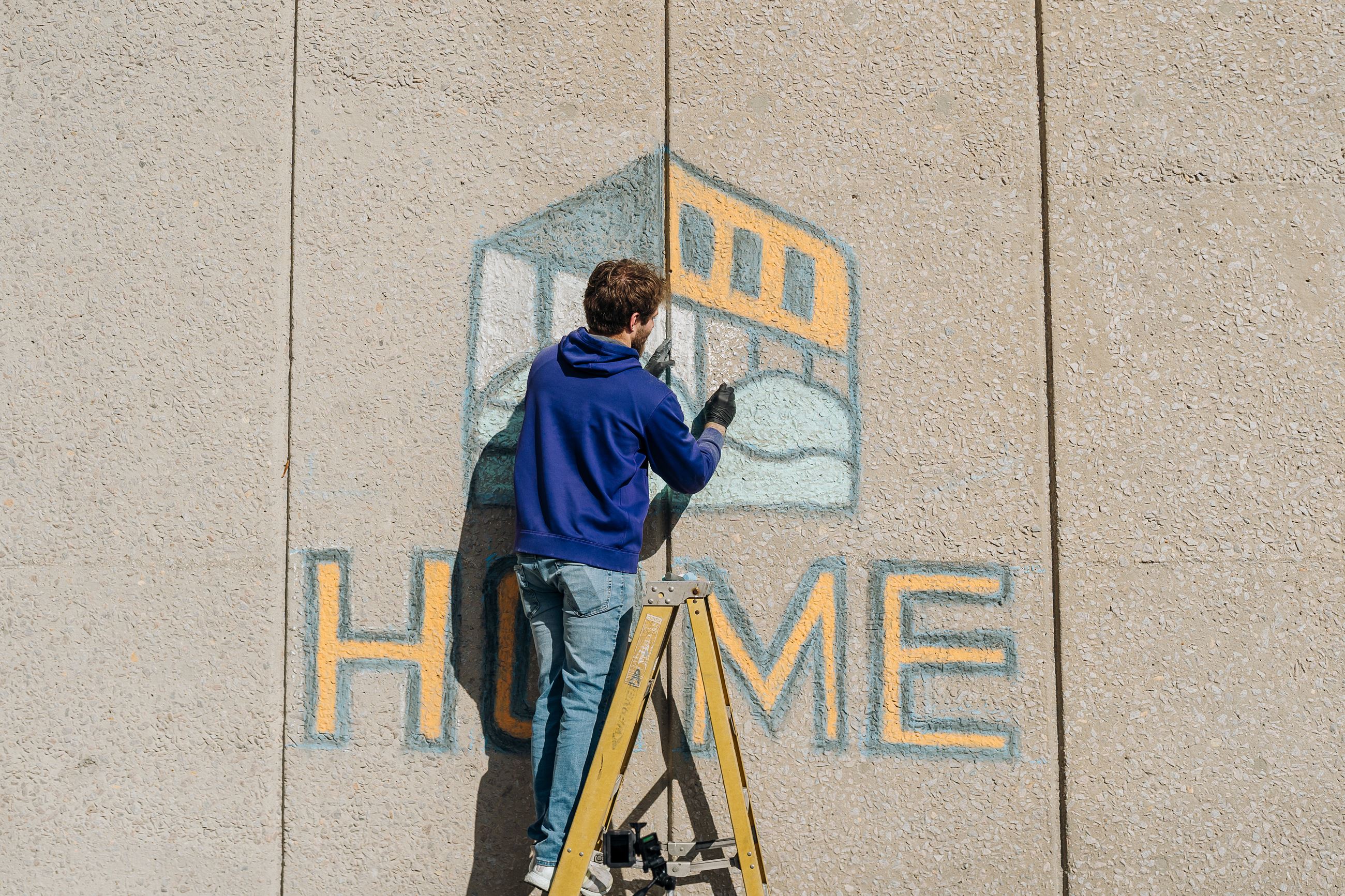 Will Justus creating the HOME logo with chalk on a building