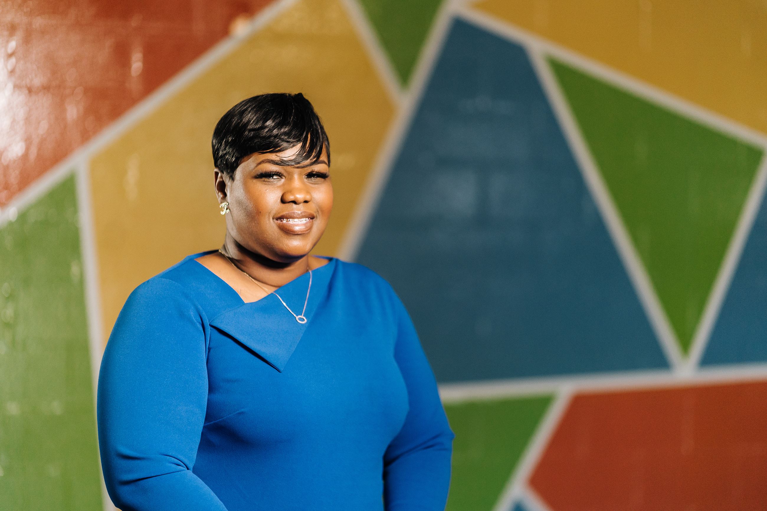 Kushana Saunders standing in front of a colorful mural. 